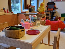 Kleiner Tisch und Sesseln mit Spielsachen aus der Puppenküche