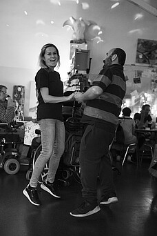 Eine Frau und ein Mann halten sich bei der Hand und tanzen lachend.