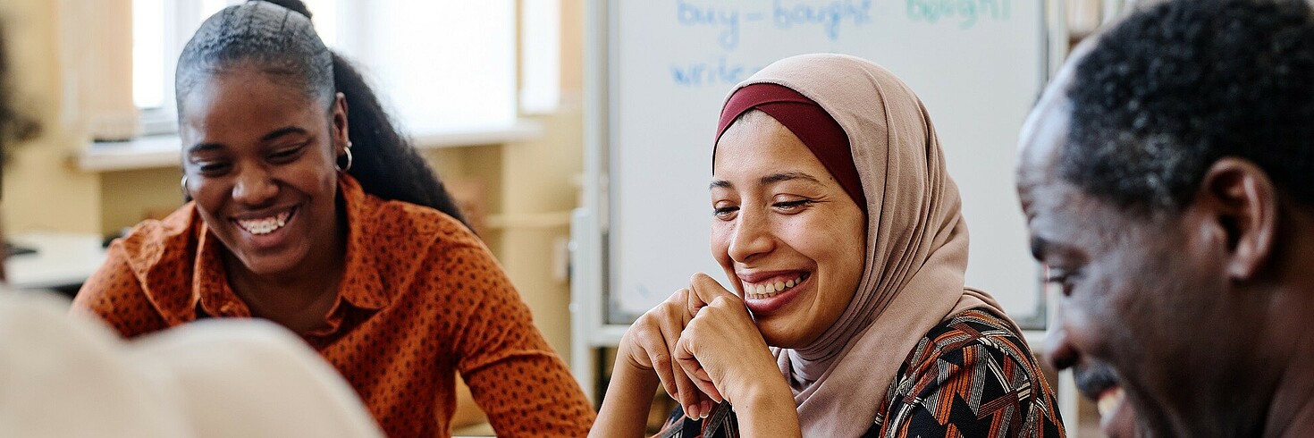 Drei Personen mit Migrationshintergrund lernen gemeinsam und lachen.