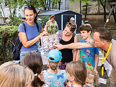 Ein Mann erklärt Kindern wie Apfelbäume wachsen.