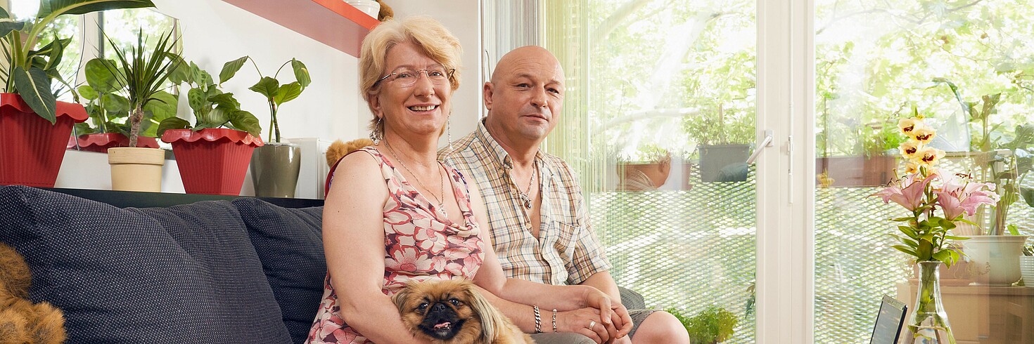 Frau und Mann sitzen in einer Wohnung auf dem Sofa