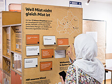 Eine Frau, die einen Hidschab trägt, betrachtet einen Info-Stand.