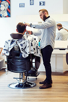 Friseur schneidet einem Kunden die Haare