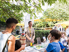 Ein Mann erklärt Kindern etwas an einem Infostand.
