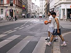 Zwei Männer überqueren mit Basketball in der Hand die Straße.