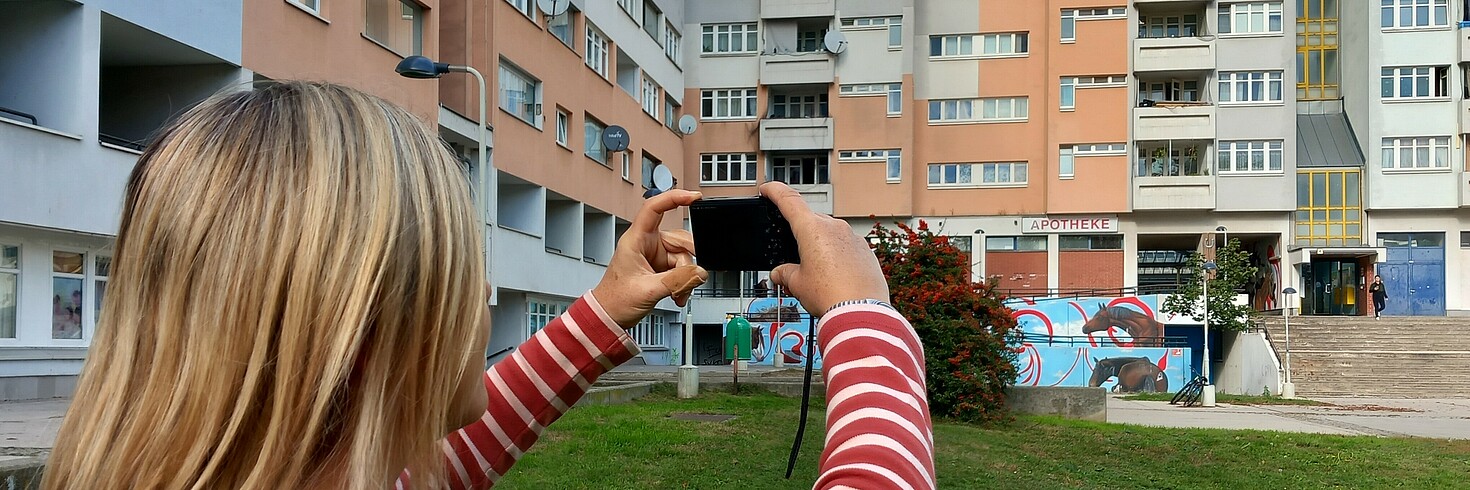 Eine Frau fotografiert ein Wohnhaus.