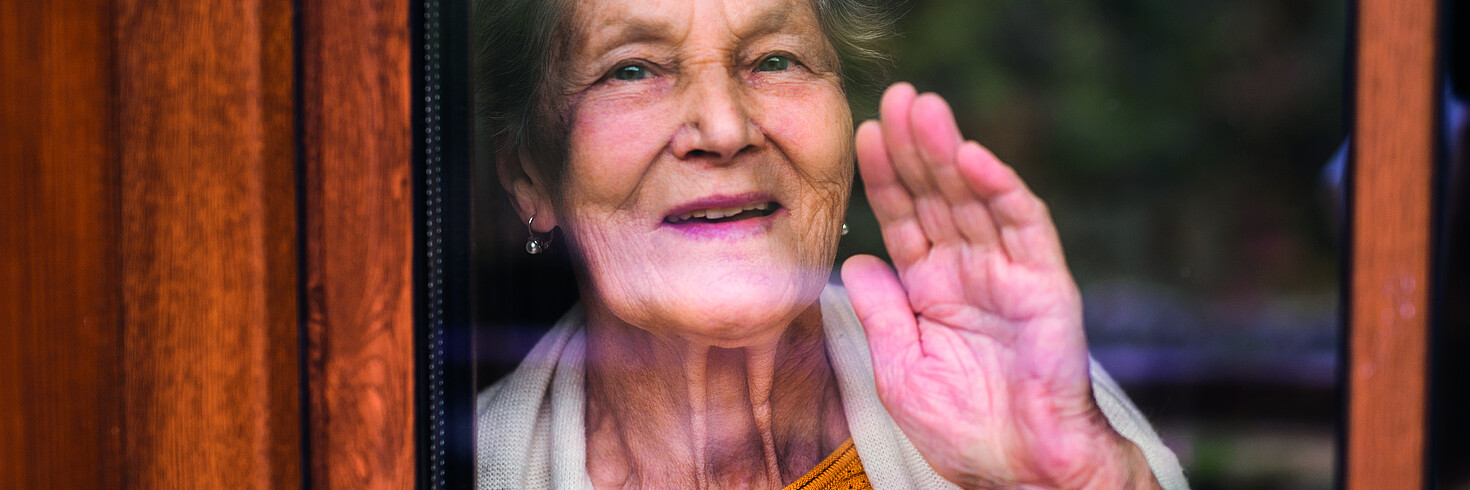 Alte Frau schaut aus dem Fenster