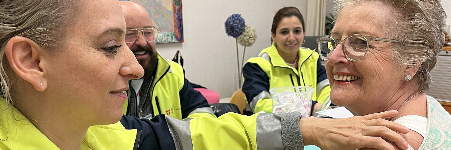 Eine junge Frau vom Gesundheitsdienst impft eine ältere, lächelnde Frau.