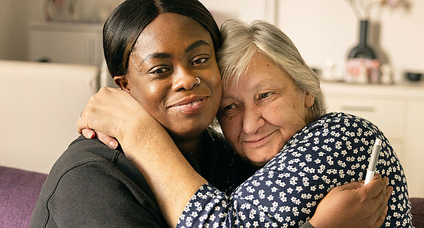 Eine Pflegerin und ihre Kundin umarmen sich.