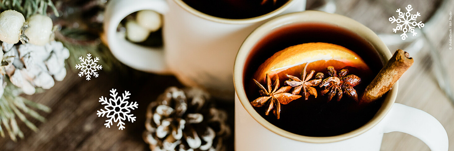 Weiße Tasse gefüllt mit Punsch und Orangenscheibe und Zimtstange dekoriert