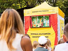 Ein Publikum schaut sich das Kasperletheater an.