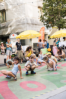 Kinder tanzen und spielen bei einem Straßenfest.