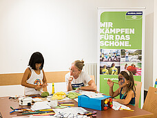 Zwei Kinder sitzen an einem Tisch von Global2000 und erhalten spielerisch Informationen.