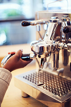 Barista macht Kaffee mit Siebträger Kaffeemaschine