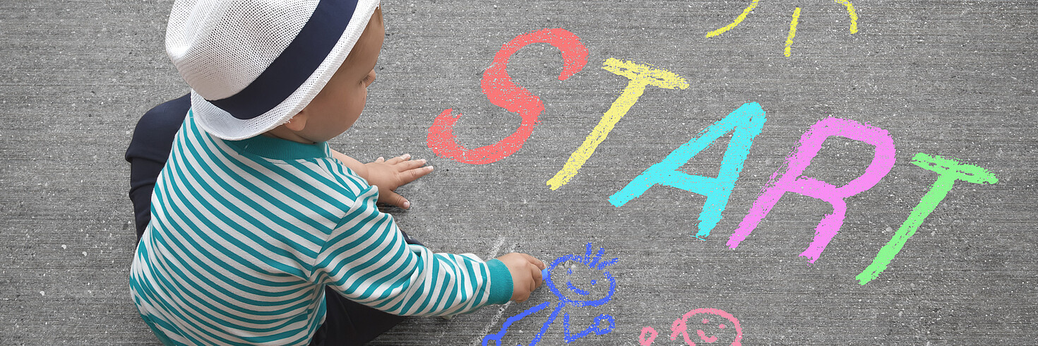 Kind malt mit Straßenmalkreide auf Asphalt