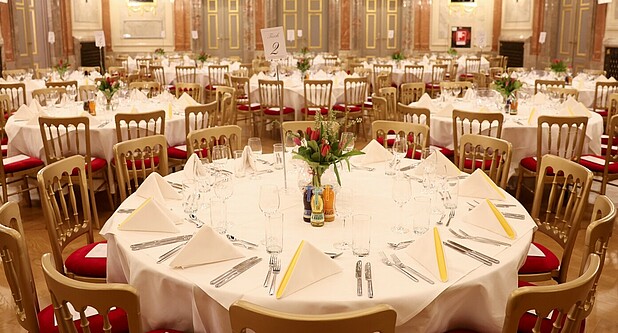 Eingedeckte Tische in einem Festsaal.