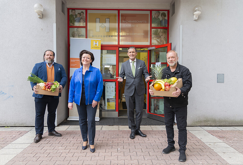 Eine Frau und drei Männer stehen vor dem Nachbarschaftszentrum Am Schöpfwerk mit Obst- und Gemüsekisten in den Händen