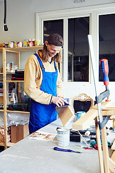 Mann schleift Holz ab in der Upcycling-Werkstatt