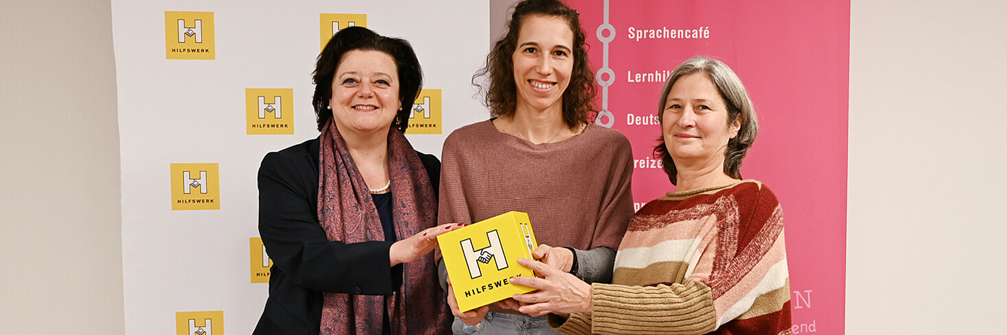 Drei Frauen lächeln in die Kamera.