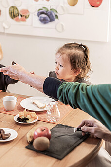 Eine Tagesmutter des Wiener Hilfswerks frühstückt mit zwei Kleinkindern.