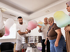 Ein Mann macht für mehrere Personen Zuckerwatte.