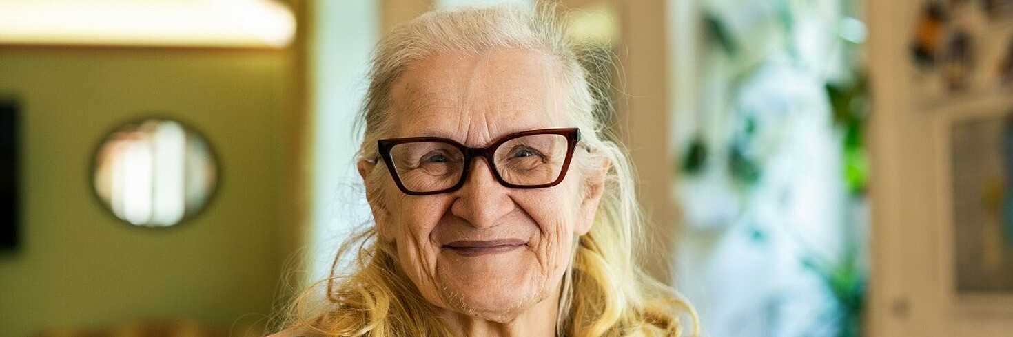 Eine Frau lächelt glücklich in die Kamera.