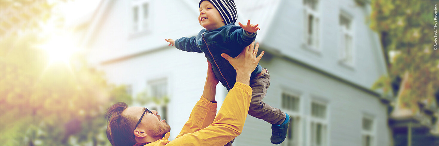 Ein Mann hält ein Kleinkind rauf. Beide lachen.